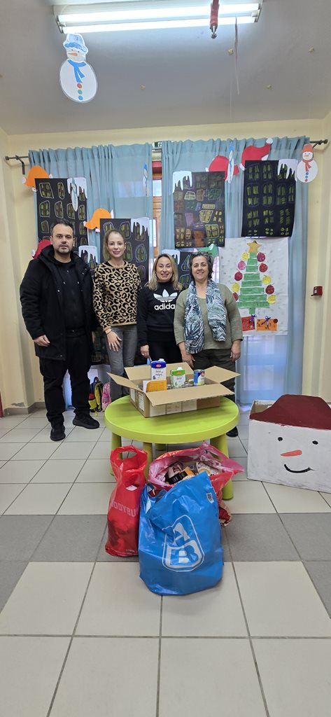 Εκπρόσωποι του 21ου Νηπιαγωγείου και του Κοινωνικού Παντοπωλείου μπροστά από τις κούτες της προσφοράς τροφίμων